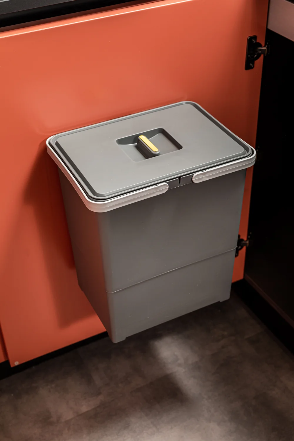 Grey Swing door-mounted waste bin with hinged lid fixed to a terracotta modular kitchen cabinet door